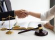 lawyer consultant with client shaking hands together with contract agreement.